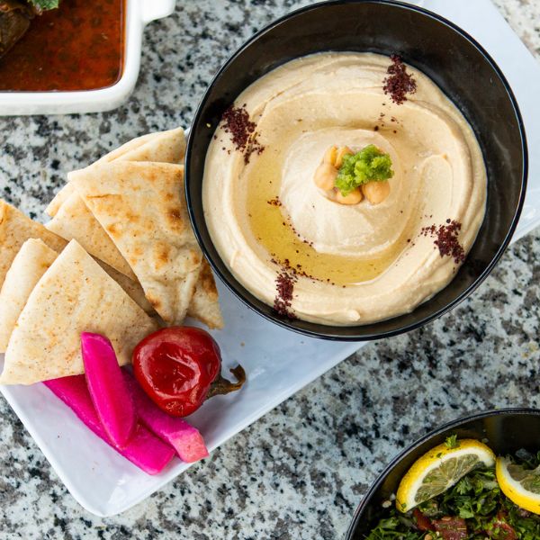 Authentic Hummus with Pita and Pickled Vegetables - A bowl of creamy hummus garnished with chickpeas and herbs, served with warm pita bread and vibrant pickled vegetables in Port St Lucie Tradition and Fort Pierce at Swift Grill