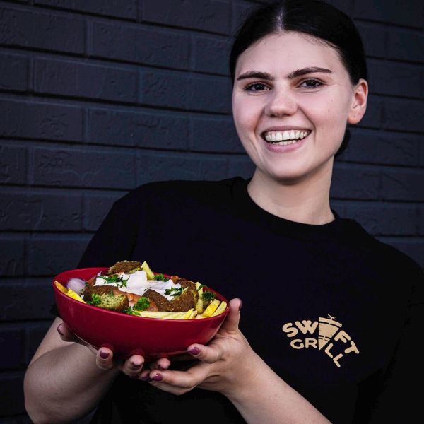 Vegetarian Mediterranean Delight - Bianca proudly holding a bowl of loaded falafel fries, showcasing the vibrant colors and fresh ingredients of this delicious vegetarian option in Port St Lucie Tradition and Fort Pierce at Swift Grill.