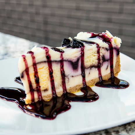 a slice of cheesecake with blueberry sauce on a white plate