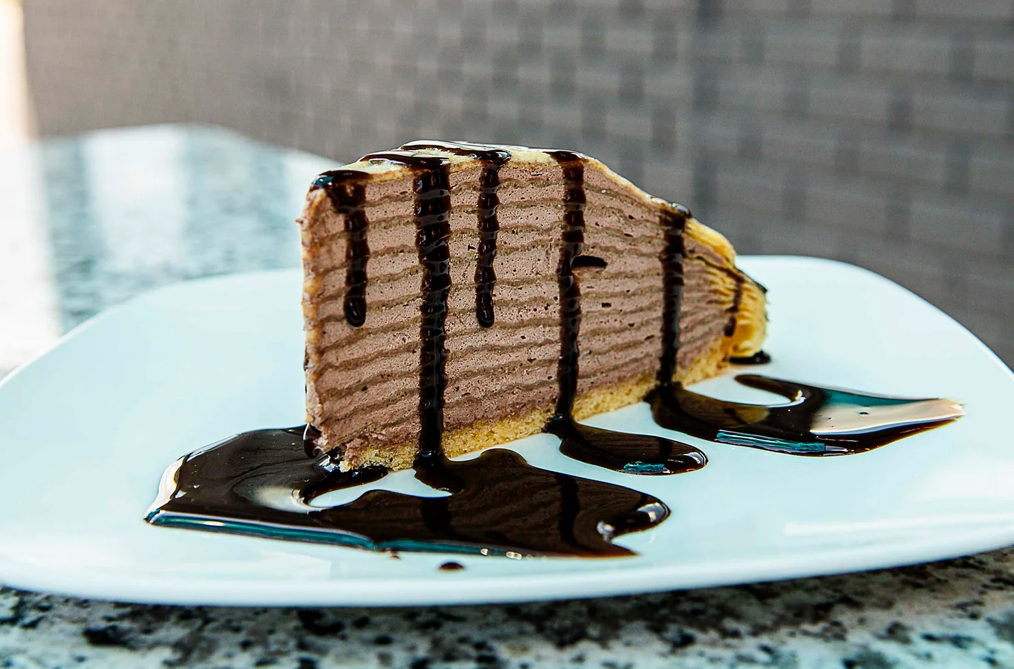 a slice of cake with chocolate sauce on a white plate