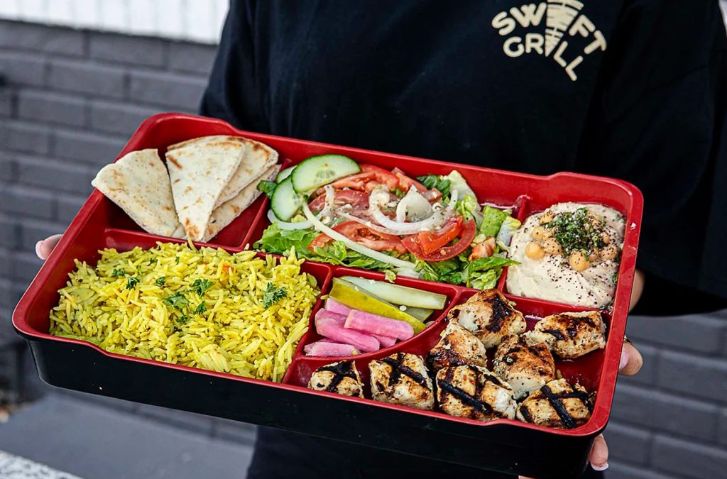 a person holding a tray of food