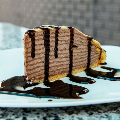 a slice of cake with chocolate sauce on a white plate