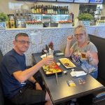 a man and woman sitting at a table with food and drinks