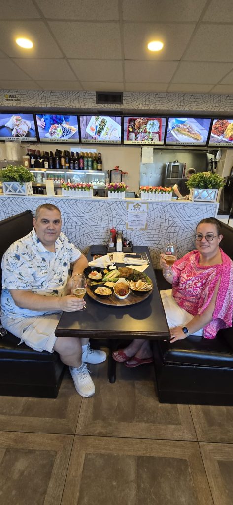 a man and woman sitting at a table with food and drinks